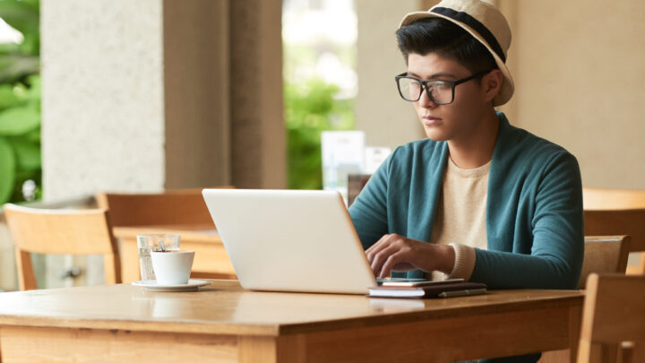A student studying with a laptop, surrounded by books and notes, creating an ideal online learning environment.