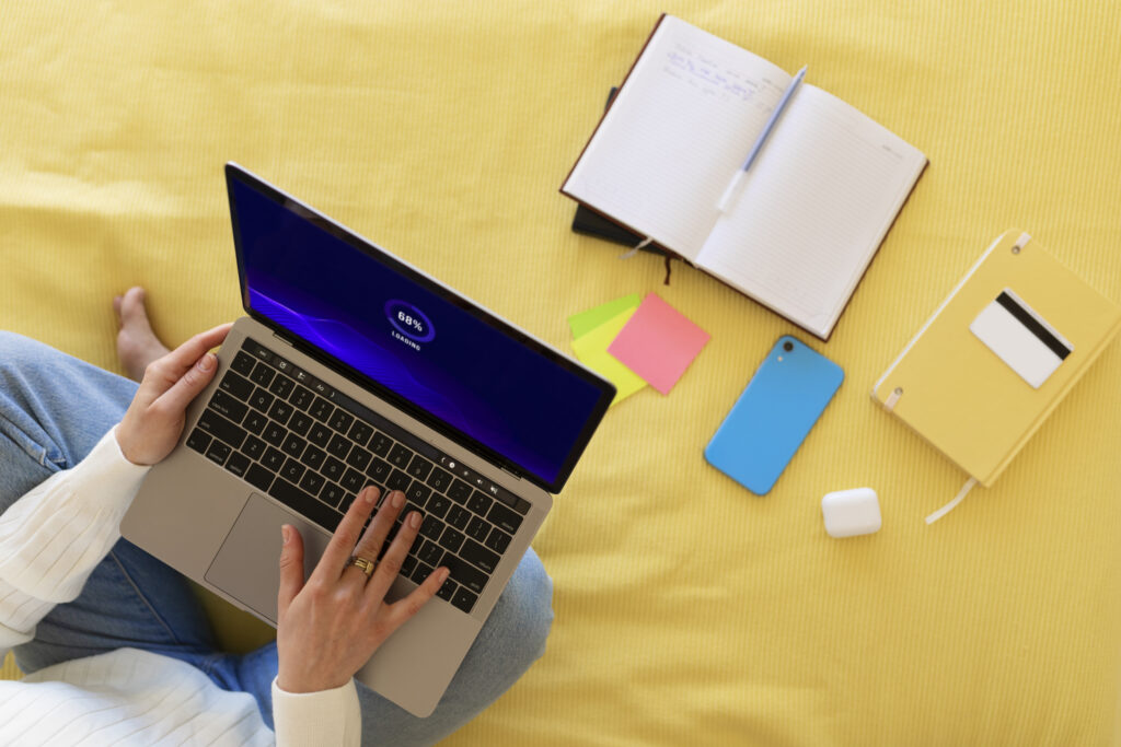 Person engaged in e-learning with a laptop surrounded by books and creative elements