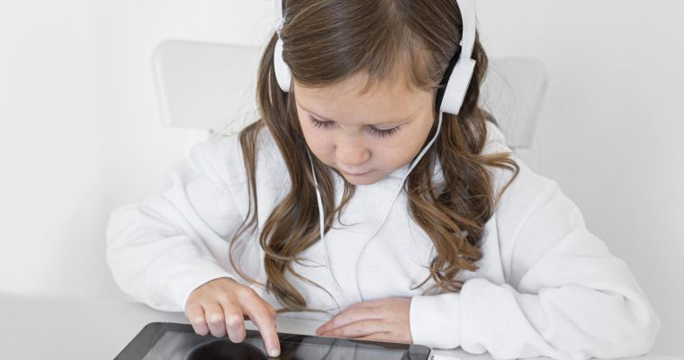 Little girl using a tablet with headphones, engaged in an eLearning activity.